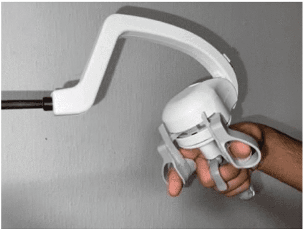 A surgeon's hand holding a handheld articulating laparoscopic instrument where wrist movement bends the tip.